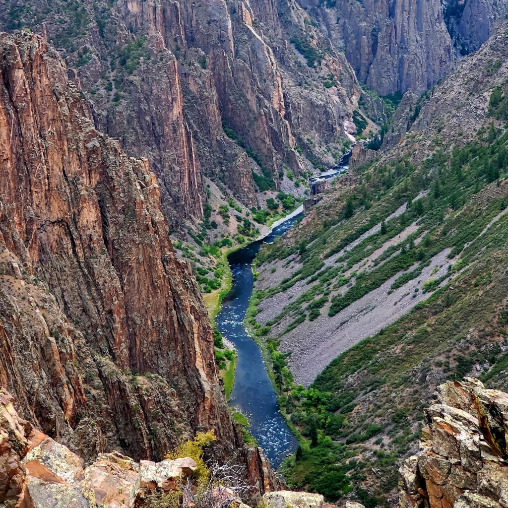 Aerial view of a winding river surrounded by steep rocky cliffs and lush greenery.