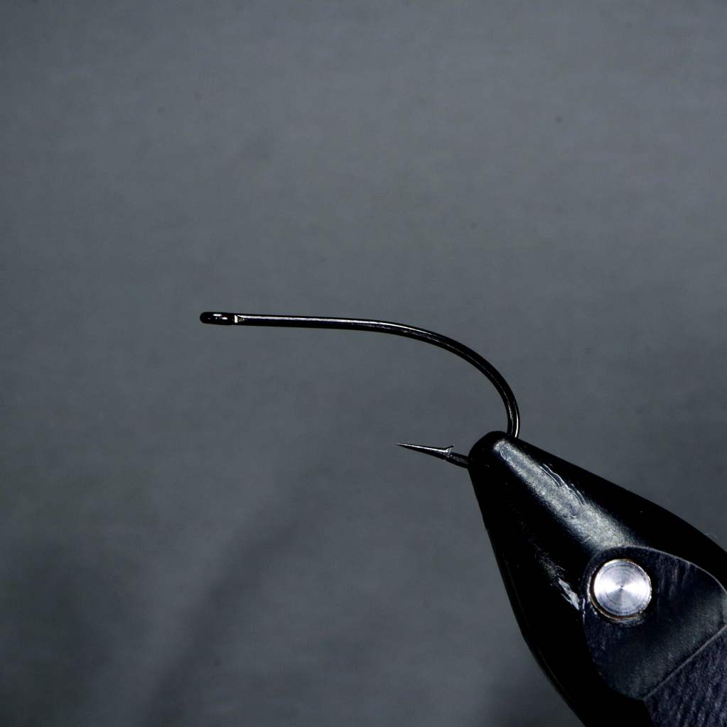 Close-up of a fly tying hook secured in a vise, ready for tying the foam-bodied Stimulator fly pattern.
